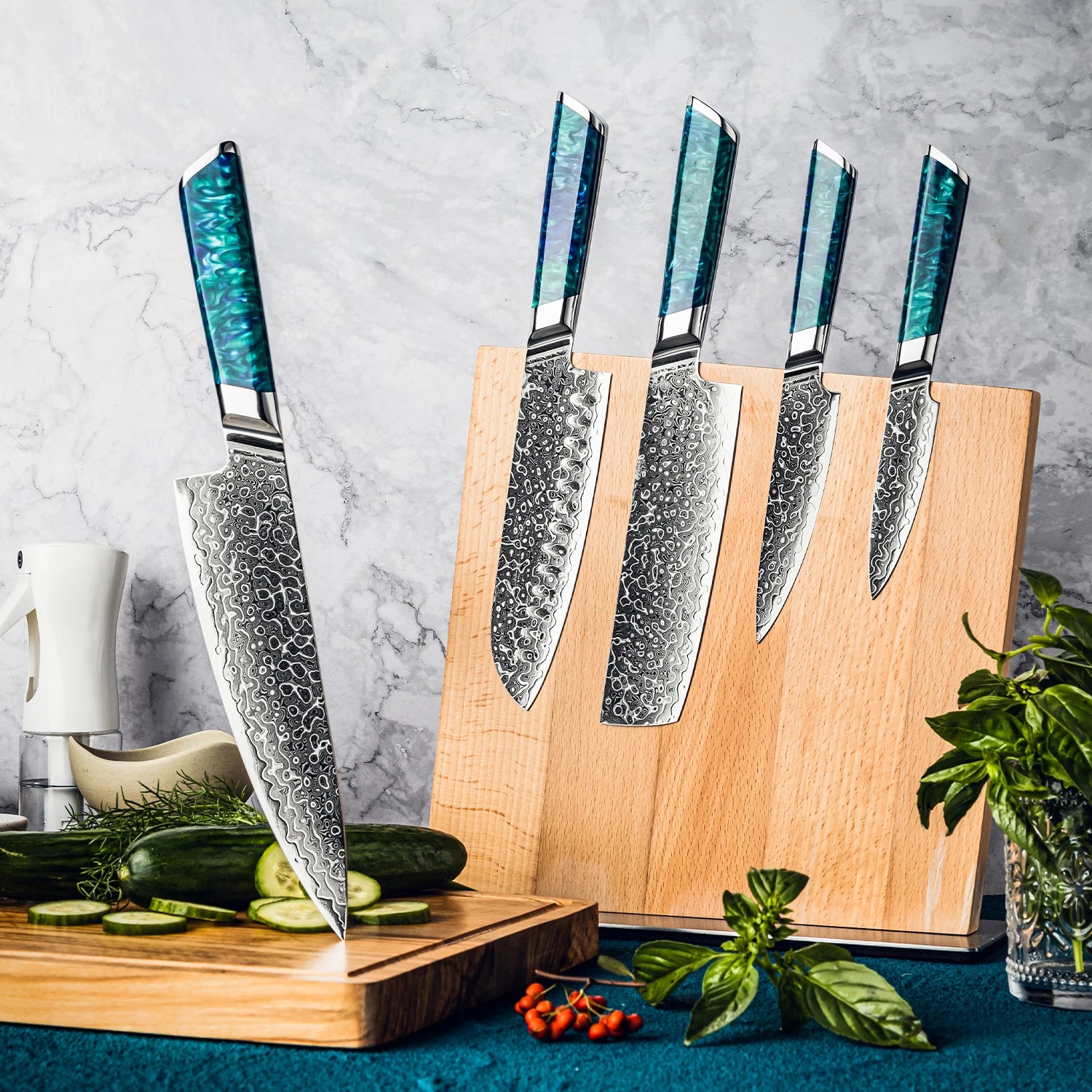 Damascus steel kitchen knife set with blue resin handles in wooden block on counter with vegetables.