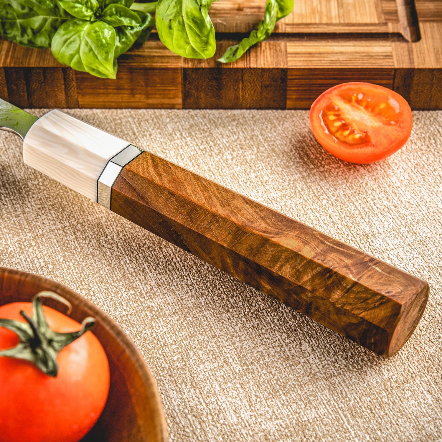 Closeup of a kitchen knife with a wooden handle, tomatoes, and a cutting board.