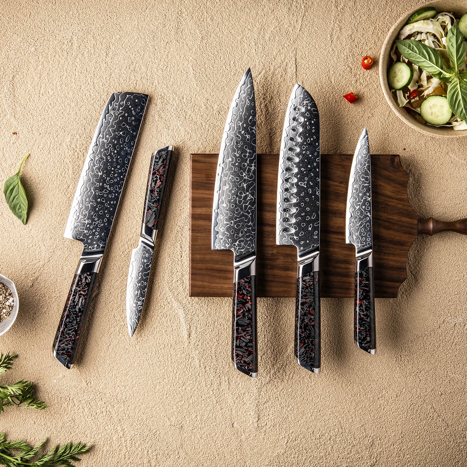 Set of patterned steel kitchen knives with dark handles on a wooden cutting board