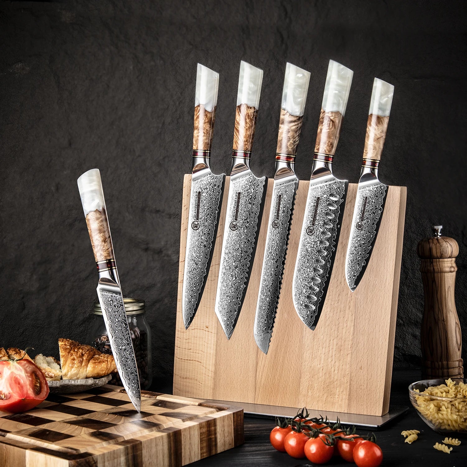 Damascus steel kitchen knife set with patterned blades and wood handles in a block on countertop