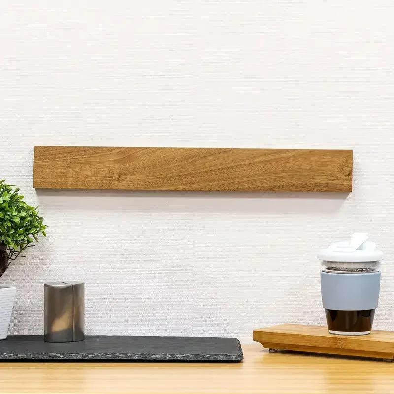 Wooden magnetic kitchen knife holder mounted on a white wall above countertop